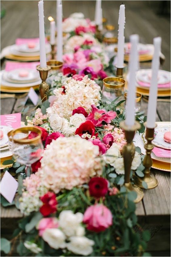 a fantastic Valentine's Day wedding table with pink and white blooms and greenery, white candles, pink menus and gold rimmed glasses