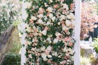 a floral wall backdrop with white and pink blooms, textural foliage in a white frame