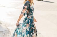 a flowy dark green maxi dress with a pink floral print, long sleeves and statement earrings