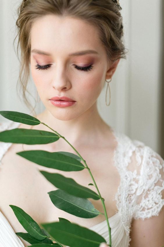 a fresh pink wedding makeup with a glossy pink lip, pink eyeshadow, a touch of blush and eyes accented with faux eyelashes