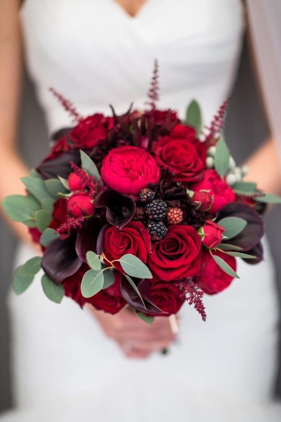 a gorgeous lush wedding bouquet of red roses, red peony roses, dark callas and greenery for a refined bridal bouquet