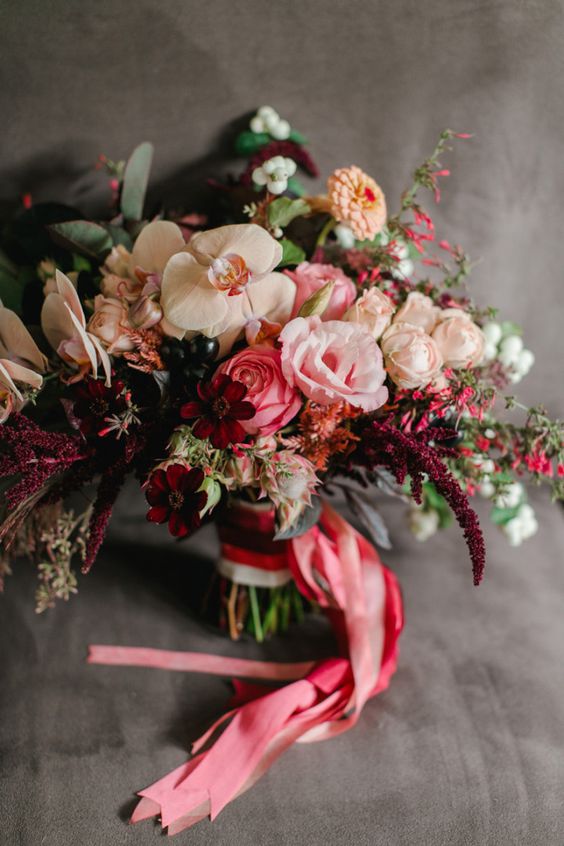 a jaw-dropping Valentine wedding bouquet of creamy, pink and deep burgundy blooms, berries and pink ribbons