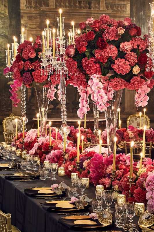 a jaw-dropping Valentine's Day wedding table with bold pink, red and fuchsia blooms, gold candles, gold candleholders and chargers