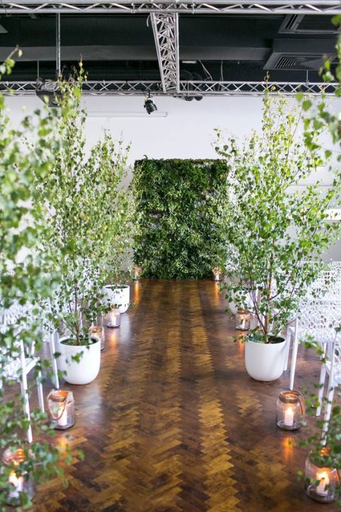 a living greenery wall and potted trees turn the indoor ceremony space into a real forest