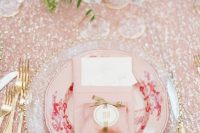 a lovely Valentine’s Day wedding table with a pink sequin tablecloth, a pink and a sheer plate, gold rimmer glasses and gold cutlery
