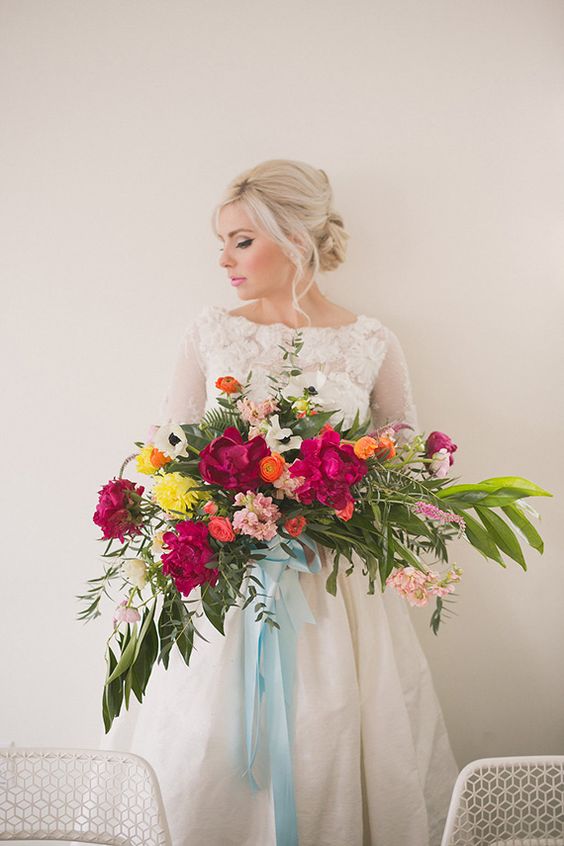 a lush and bold Valentine's Day wedding bouquet of light pink, fuchsia, orange, yellow blooms and leaves