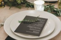 a minimalist winter wedding tablescape done in neutrals and black, with greenery and gilded touches