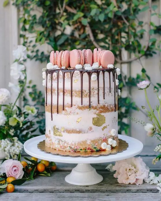 a naked cake with chocolate drip, meringues, pink macarons and gold leaf is a fresh and pretty idea for a cute spring wedding