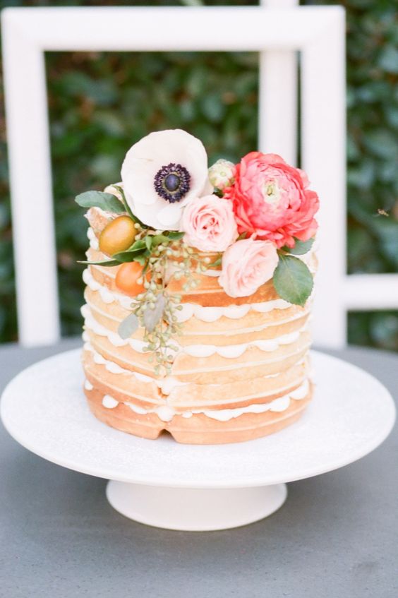 a naked pancake wedding cake with pink, white and coral blooms, citrus and greenery is a cool idea for a bright spring wedding
