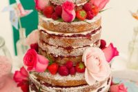 a naked wedding cake decorated with pink and blush roses, strawberries and raspberries is amazing for Valentine weddings