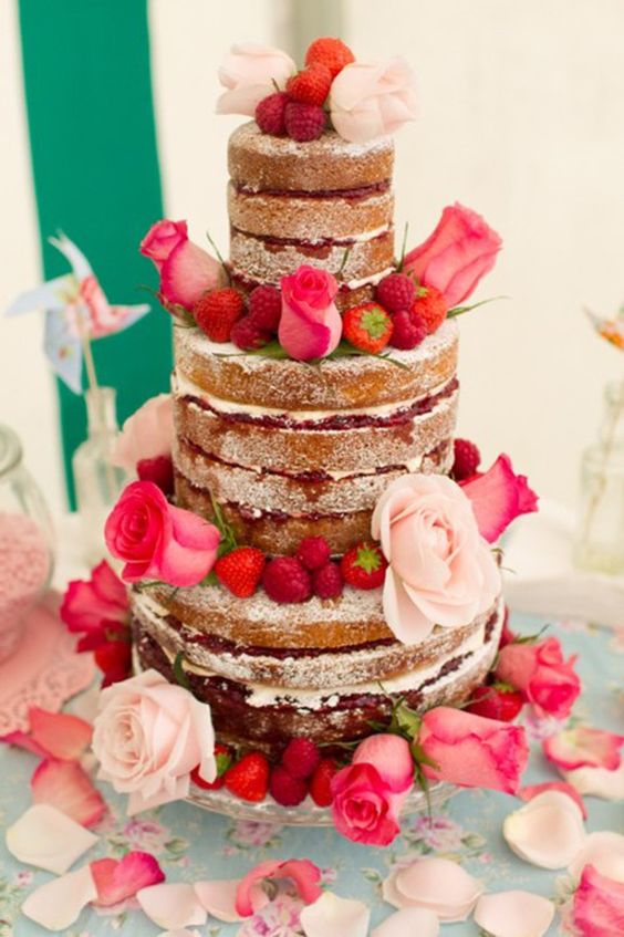 a naked wedding cake decorated with pink and blush roses, strawberries and raspberries is amazing for Valentine weddings