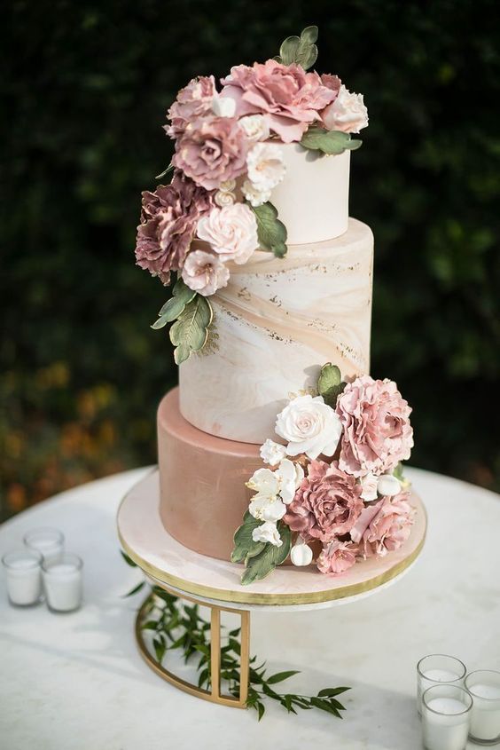 a neutral and mauve wedding cake decorated with mauve and neutral blooms and greenery of sugar is amazing