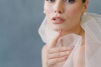 a neutral wedding makeup with a touch of blush, a glossy pink lip, a touch of blush eyeshadow and accented eyebrows