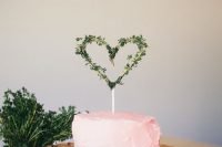 a pink buttercream one tier wedding cake topped with a greenery heart is a casual idea for a Valentine wedding