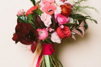 a pretty Valentine wedding bouquet of burgundy, pink, red and blush blooms and greenery and colorful ribbons