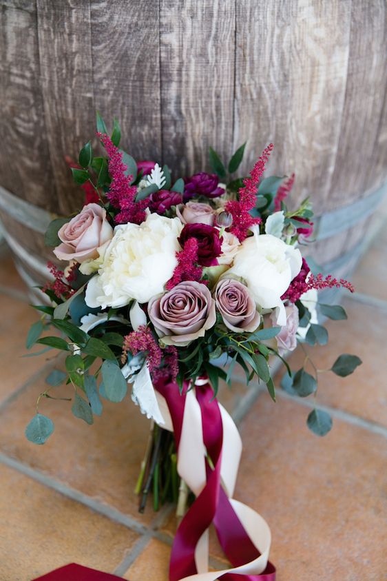 a pretty Valentine wedding bouquet of mauve, white and fuchsia and purple blooms, greenery and bright ribbons