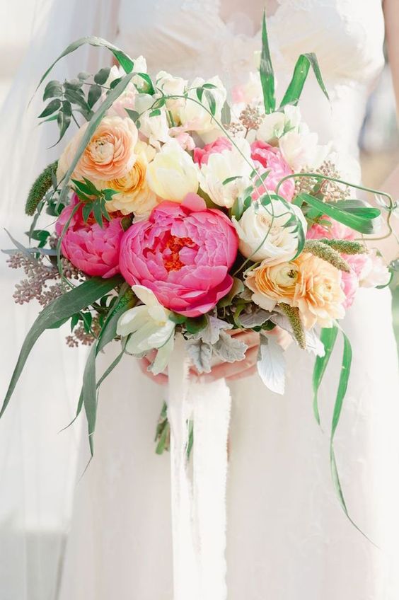a pretty and vivacious Valentine wedding bouquet of yellow, white and pink blooms and greenery and white ribbons