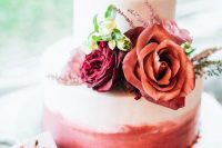 a pretty ombre pink wedding cake topped with burgundy, red and blush ones and greenery is ideal for Valentine weddings