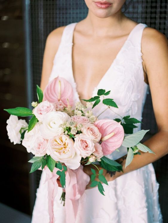 a pretty romantic Valentine wedding bouquet of light pink, blush and white roses, peony roses and tropical blooms plus foliage