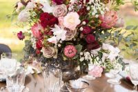 a refined Valentine wedding centerpiece of a vintage urn, pink, blush, burgundy blooms and greenery looks catchy