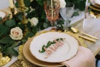 a refined and beautiful Valentine’s Day weddig table with white and blush blooms, gold chargers and cutlery, greenery and neutral candles
