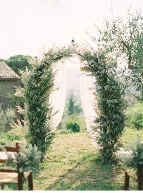 a rustic greenery arbor and wedding chair decor perfectly fit the casual elegance of the Tuscan countryside