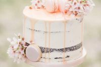 a semi naked wedding cake with blush drip, cherry blossom and blush macarons is amazing for spring thanks to its blooms