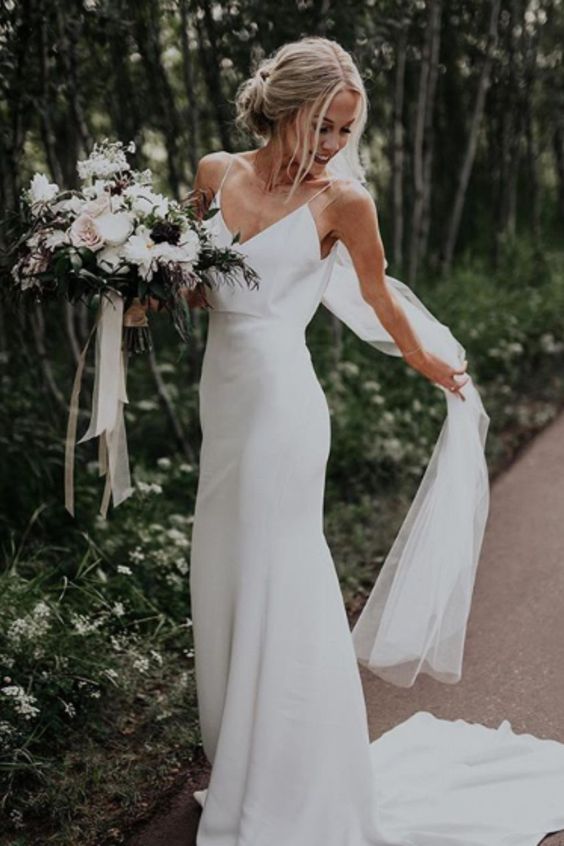 a sheath slip plain wedding dress and a veil for a chic minimalist bridal look