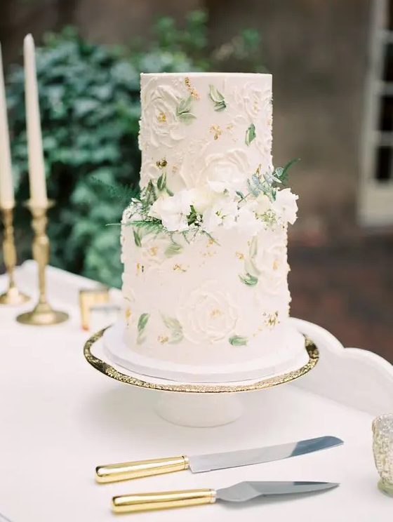 a sophisticated spring wedding cake in neutrals with sugar blooms and painted leaves, with fresh white flowers and ferns is amazing