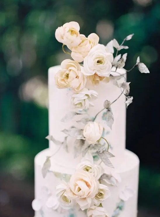 a subtle wedding cake in white, with neutral blooms and spray painted leaves is a very chic and beautiful idea for a neutral spring wedding