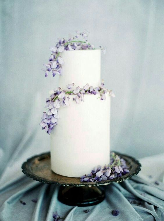 a subtle white buttercream wedding cake topped with lilac blooms is an amazing idea for spring celebrations with a pastel color palette