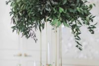 a tall centerpiece on a gold stand with lush greenery is an elegant modern idea to rock