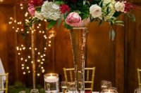 a tall glass vase with white, burgundy and pink blooms and greenery is a stylish and chic floral centerpiece to try