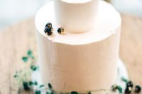 a textural buttercream wedding cake topped with foliage and with gilded berries