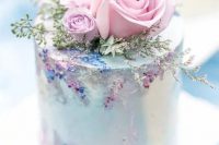 a very delicate and refined pastel wedding cake in light blue, with pink roses and greenery and sugar detailing is amazing for a secret garden wedding