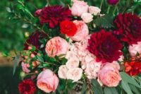 a vibrant floral centerpiece of a vintage vase with blush, red and burgundy blooms and greenery for a Valentine wedding