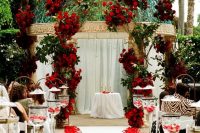 a wedding altar done with red roses, greenery and red rose petals on the floor is a fantastic idea for Valentine’s Day