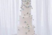 a white buttercream wedding cake topped with lilac and blue sugar blooms is a delicate and chic solution for a spring wedding