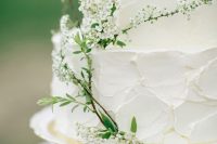 a white textural buttercream wedding cake decorated with white blooming branches is a lovely idea for a spring wedding