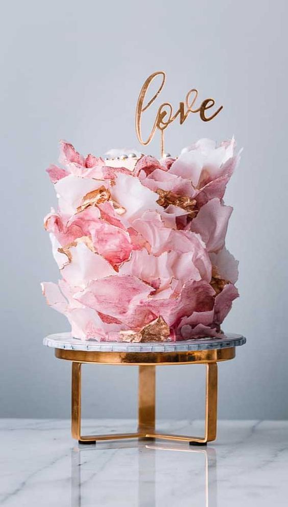 an incredible pink and gold shard and petal wedding cake topped with a matching LOVE topper is great