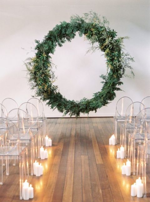 an oversized circular greenery wedding arch floating in the air, ghost chairs and candles