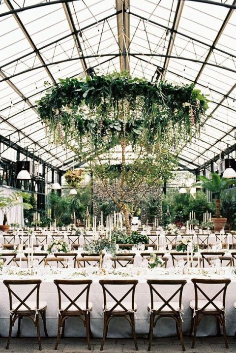 lush and large greenery chandelier with cascading elements and a living wall turn an indoor space into an outdoor one