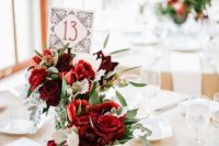simple red rose centerpieces with usual and pale greenery and an art deco table number for a Valentine’s Day