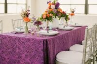 the wedding tablescape done with a purple printed tablecloth, bright florals and geometric candle holders