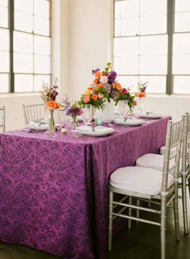 the wedding tablescape done with a purple printed tablecloth, bright florals and geometric candle holders