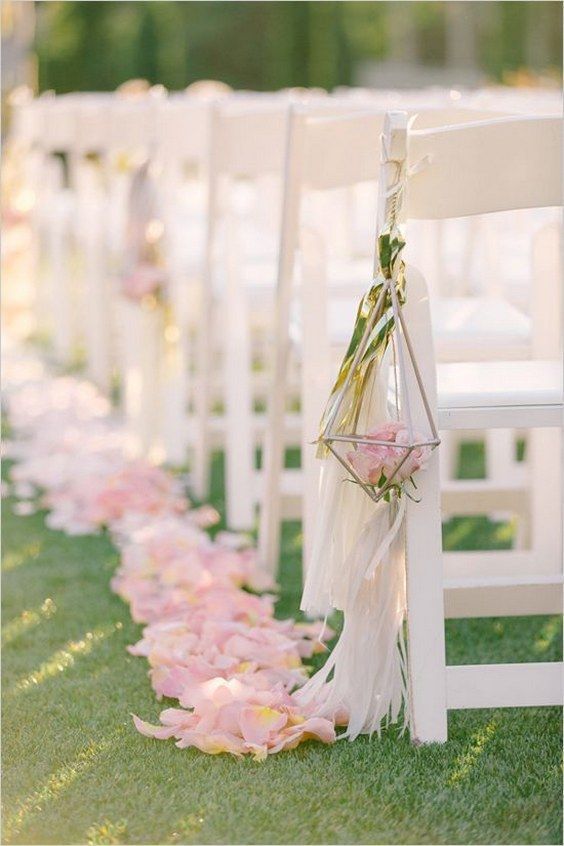 a beautiful and breezy sprign wedding aisle with pink petals on the ground and a cage with pink roses and long tassels is wow