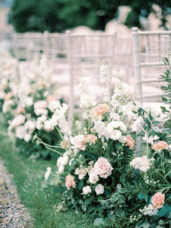 a beautiful and chic spring wedding aisle with lots of greenery, white and blush blooms is a delicate and lovely idea to try