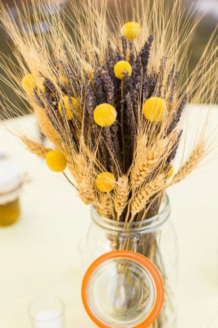 a beautiful and easy wedding centerpiece of a jar with wheat, billy balls and lavender is a cool rustic idea that you can DIY