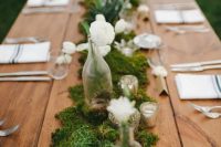 a beautiful backyard wedding tablescape with a moss and white bloom runner, striped napkins and chic candleholders is a lovely idea