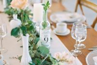 a beautiful backyard wedding tablescape with a neutral runner, greenery, pastel and white blooms and crystal chargers